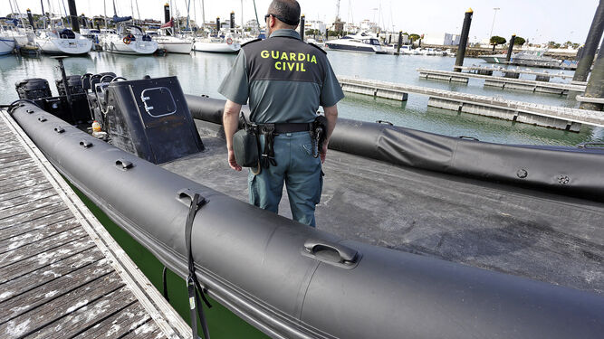 Un agente del Servicio Marítimo de la Guardia Civil en la goma intervenida, que se encontraba ayer en el puerto de Chipiona.