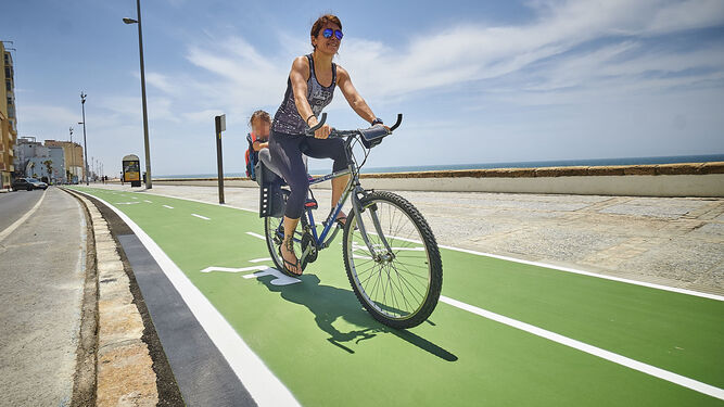 Una ciclista se traslada con su hijo por el carril bici que atraviesa el Paseo Marítimo.